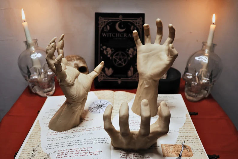 Mani scultoree disposte su un altare con candele accese e simboli occulti