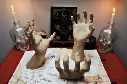 Mani scultoree disposte su un altare con candele accese e simboli occulti