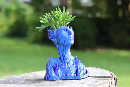 Vaso blu a forma di busto umano con pianta grassa sulla sommità