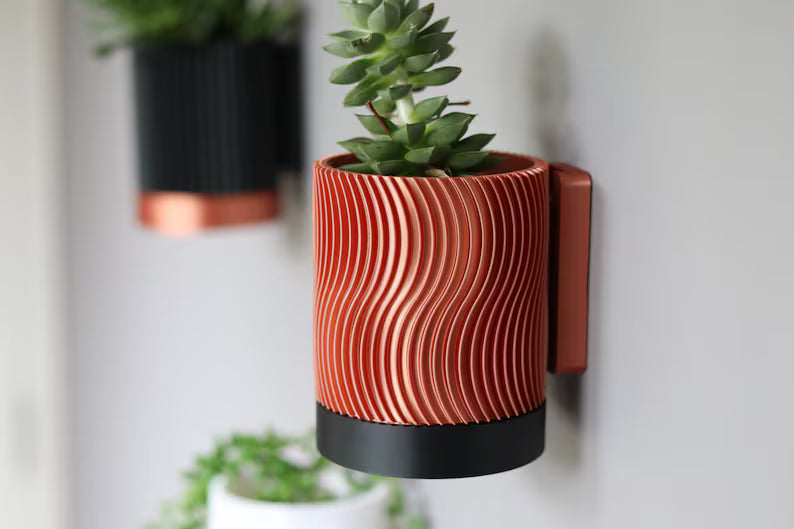 Vaso da parete arancione con texture ondulata e pianta verde