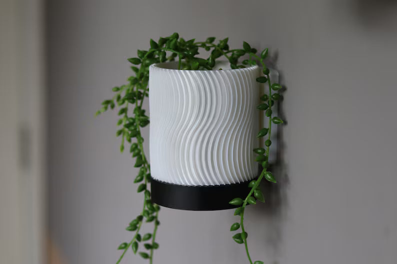 Vaso da parete bianco con motivo ondulato e pianta ricadente verde