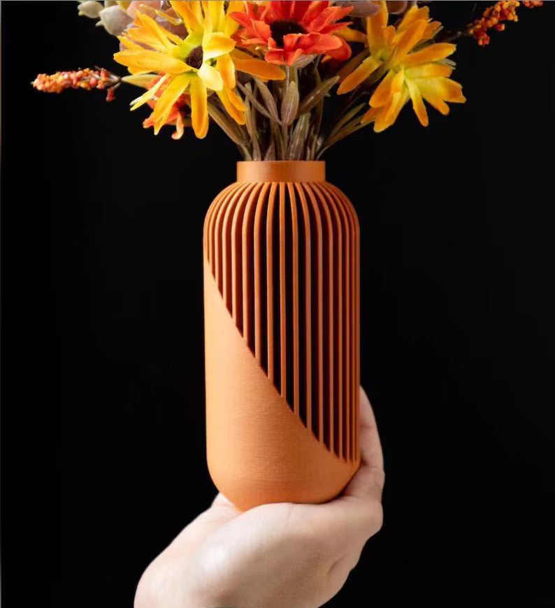 Vaso decorativo color terracotta con fiori gialli tenuto in mano su sfondo scuro